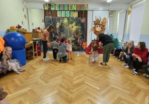Bal "W jesiennym lesie" - dzieci doczepiają kółka do sylwety muchomora