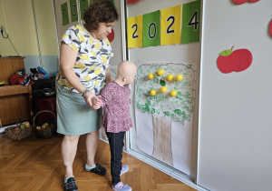 Światowy Dzień Jabłka - dziecko przyczepia żółte kulki do konturu drzewa
