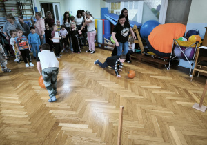 Dwóch chłopców toczy dynie po podłodze
