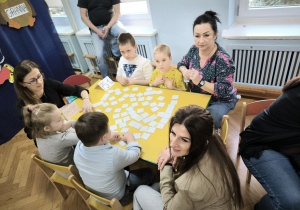 Dzieci z Przedszkola Miejskiego 185 oraz Przedszkola Miejskiego Specjalnego nr 1 rywalizują w grach planszowych siedząc przy stoliku wraz z opiekunkami