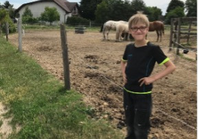 Hipoterapia - chłopiec stoi na tle koni