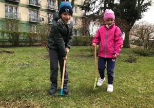 Dwoje dzieci grabi i trzyma szpadel