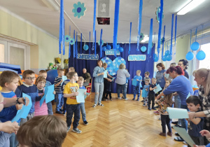 Dzieci tańczą z niebieskimi kartkami