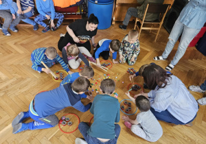 Dzieci zbierają szczypcami kolorowe pomponiki