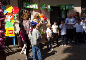 Pani dyrektor mówi przez mikrofon i wręcza dyplomy dzieciom kończącym edukację przedszkolną