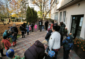 Dzieci stoją w kole na dziedzińcu przedszkola