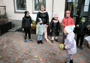 Dziewczynka w czapce i okularach trzyma w rękach kolorową piłkę