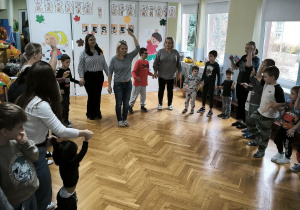 Dzieci stoją w kole i podnoszą ręce i nogi na znak nauczyciela