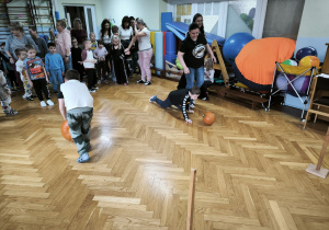 Dwóch chłopców toczy dynie po podłodze