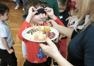 Chłopiec podgląda jakie owoce i warzywa podaje mu nauczycielka