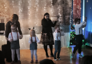 Dzieci z grupy Krasnoludków występują przed rodzicami, dzieci mają założone czerwone szelki