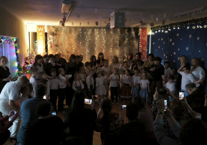 Wszystkie dzieci stoją na środku sali z nauczycielkami i pomocami nauczycielek