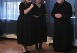 Dyrektor Przeszkola wypowiada się do zaproszonych gości, po prawej stronie stoi nauczycielka i zaproszony ksiądz z Parafii Św. Antoniego Padewskiego w Łodzi