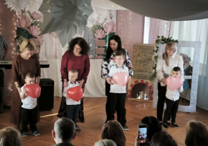 Dzieci z grupy Pszczółek tańczą trzymając czerwone, balonowe serca w dłoniach