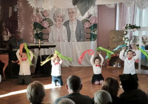 Dzieci z grupy Zajączków występują trzymając zielone, czerwone i niebieskie szarfy przymocowane do kółek