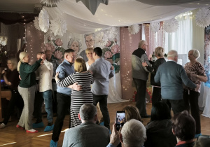 Czworo dziadków i czworo babć tańczy na środku sali