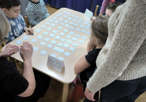 Dzieci z Przedszkola Miejskiego 206 oraz Przedszkola Miejskiego 36 rywalizują w grach planszowych siedząc przy stoliku wraz z opiekunkami