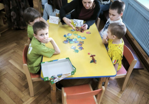 Dzieci z Przedszkola Miejskiego 221 oraz Przedszkola Miejskiego Specjalnego nr 1 rywalizują w grach planszowych siedząc przy stoliku wraz z opiekunkami