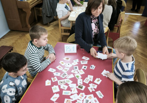 Dzieci z Przedszkola Miejskiego 206 oraz Przedszkola Miejskiego Specjalnego nr 1 rywalizują w grach planszowych siedząc przy stoliku wraz z opiekunkami