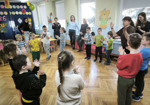 Dzieci z biorące udział w olimpiadzie stoją w kręgu i klaszczą w dłonie