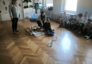 Chłopiec w okularach siedzi na plastikowych sankach