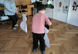 Chłopiec przyczepia elementy ubioru do postaci bałwana