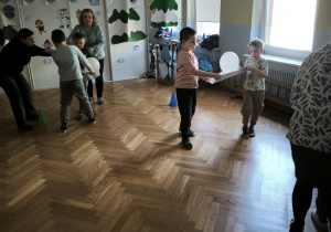 Dzieci przenoszą balon trzymając go we dwójkę na kartce papieru