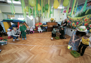 Chłopcy przeciągają wiaderko z piłką, aby umieścić ją w zielonej misce