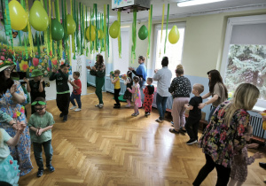 Dzieci i nauczycielki wędrują wkoło po sali klaszcząc w dłonie