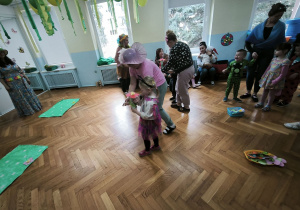 Dziewczynka przebrana za motyla niesie kwiatka, aby umieścić go na podłodze, na zielonym kartonie
