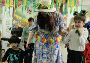 Chłopcy z grupy Tygrysków spacerują z nauczycielką po zielonym płótnie. Wokół dzieci latają mydlane bańki