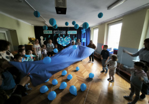 Dzieci podrzucają niebieskie balony z użyciem błękitnego płótna