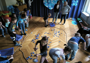 Pierwsza grupa dzieci łowi niebieskie rybki za pomocą wędek i wkłada rybki do pojemników