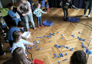 Druga grupa dzieci łowi niebieskie rybki za pomocą wędek i wkłada rybki do pojemników