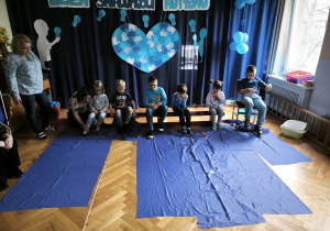 Pierwsza grupa dzieci zwija niebieskie płótno przy użyciu nóg