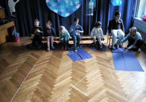 Druga grupa dzieci zwija niebieskie płótno przy użyciu nóg