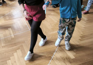 Chłopiec pokonuje tor i kładzie na podłodze wycięte z papieru figury geometryczne