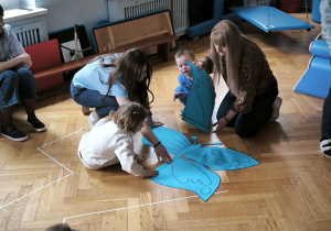 Dzieci układają na podłodze niebieskiego motyla