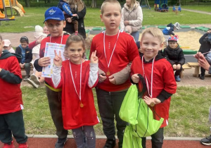 Dzieci z grupy "Zajączkow" ubrane w czerwone koszulki stoją z medalami na szyjach
